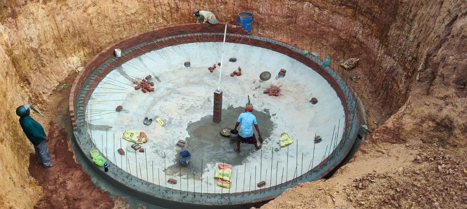 Workers laying base slab in biogas pit